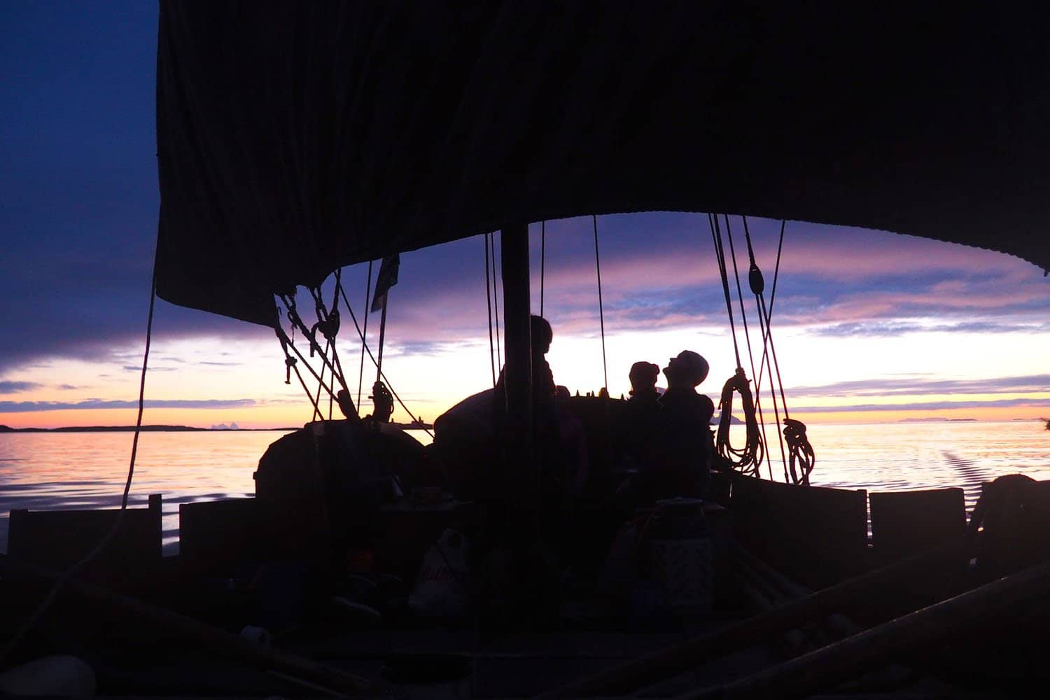 A square-rigged wooden boat at sunset