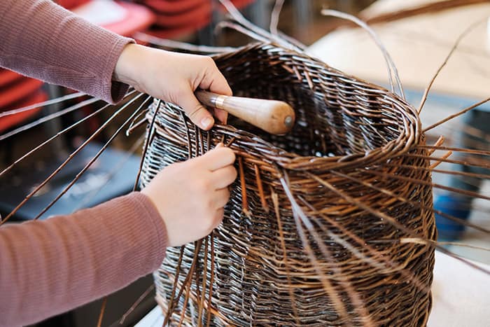 Student weaving a willow basket