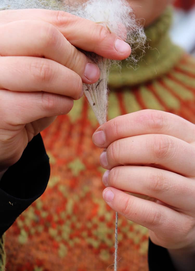 students spinning woollen yarn on a drop spindle